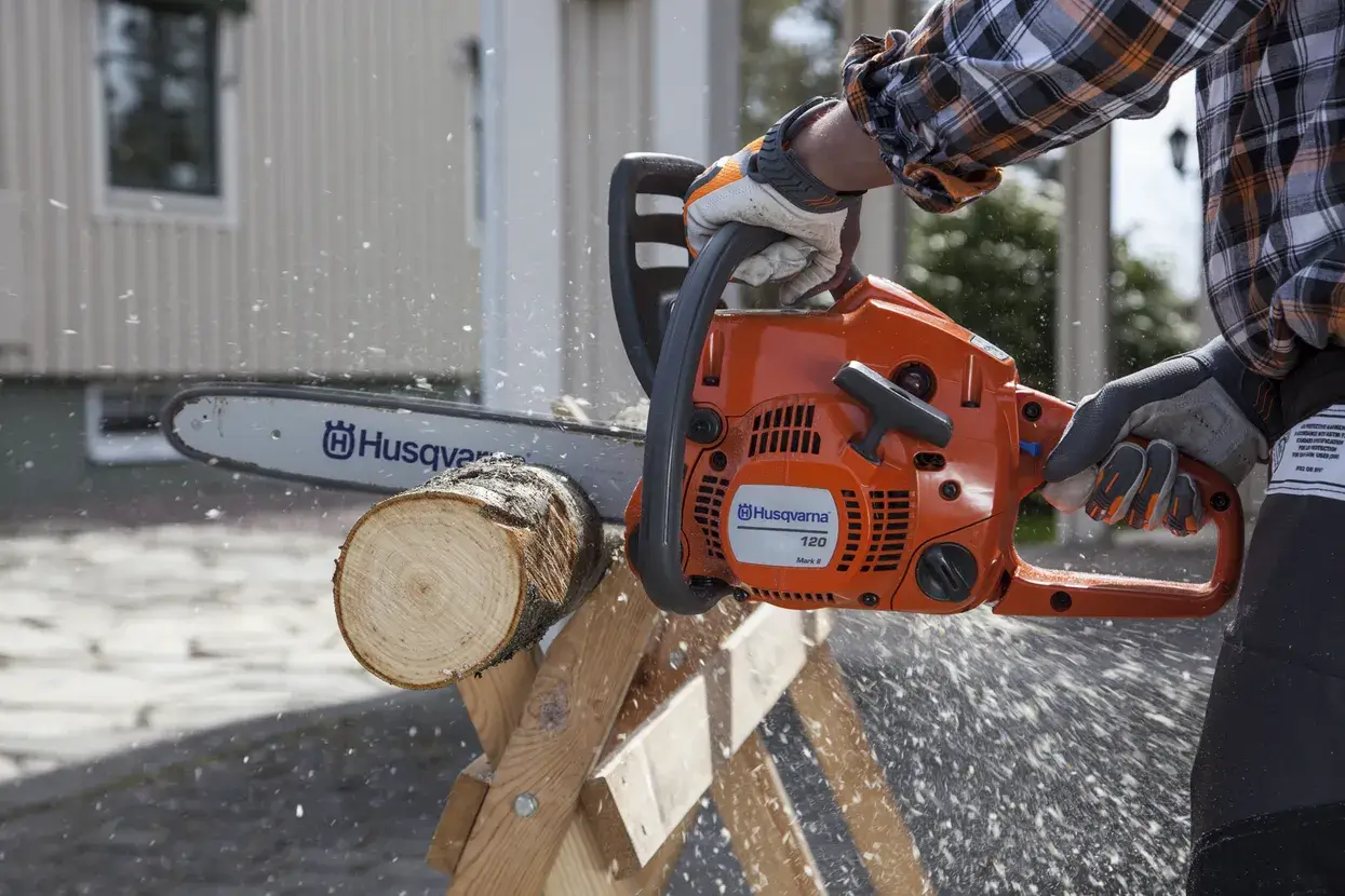 Husqvarna 120 Mark II en coupe sur une bûche posée au sol