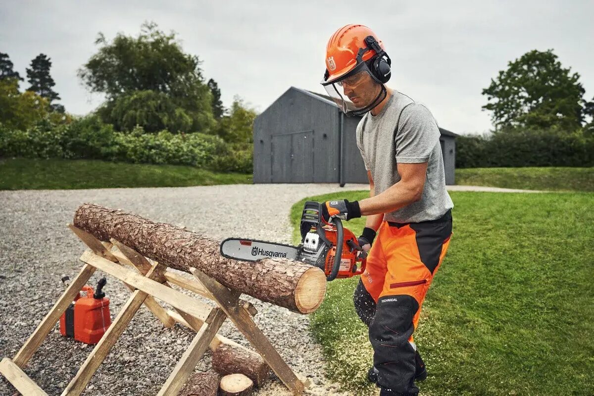 Utilisateur en équipement de protection débitant une bûche à la Husqvarna 440 II