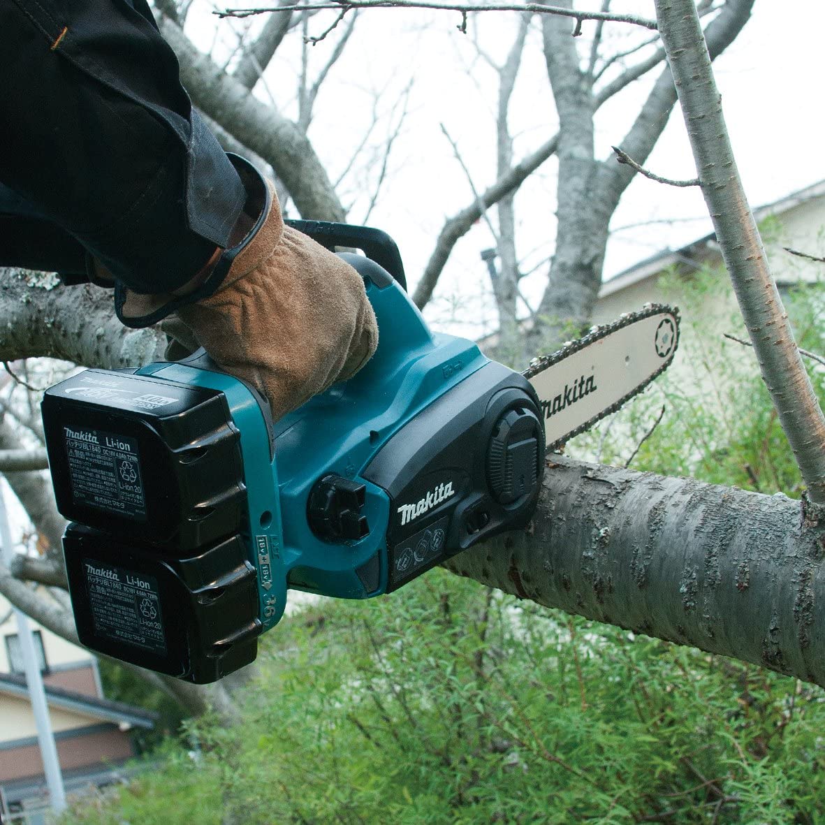 Makita DUC252Z tenue à une main pour couper une branche, ses deux batteries 18 V en place