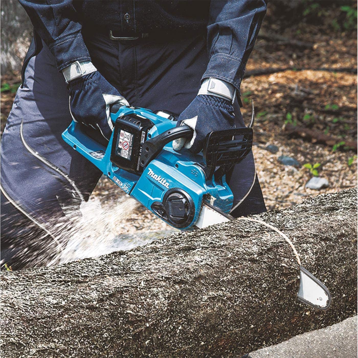 Makita DUC353Z tenue à deux mains en train de tronçonner un tronc couché au sol