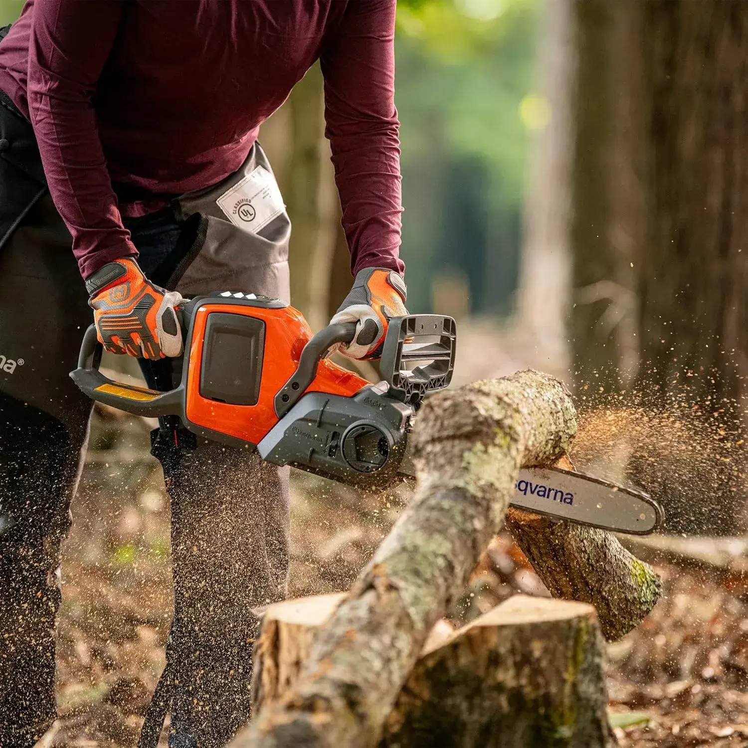 Husqvarna 225i en coupe sur une branche, logement de batterie visible