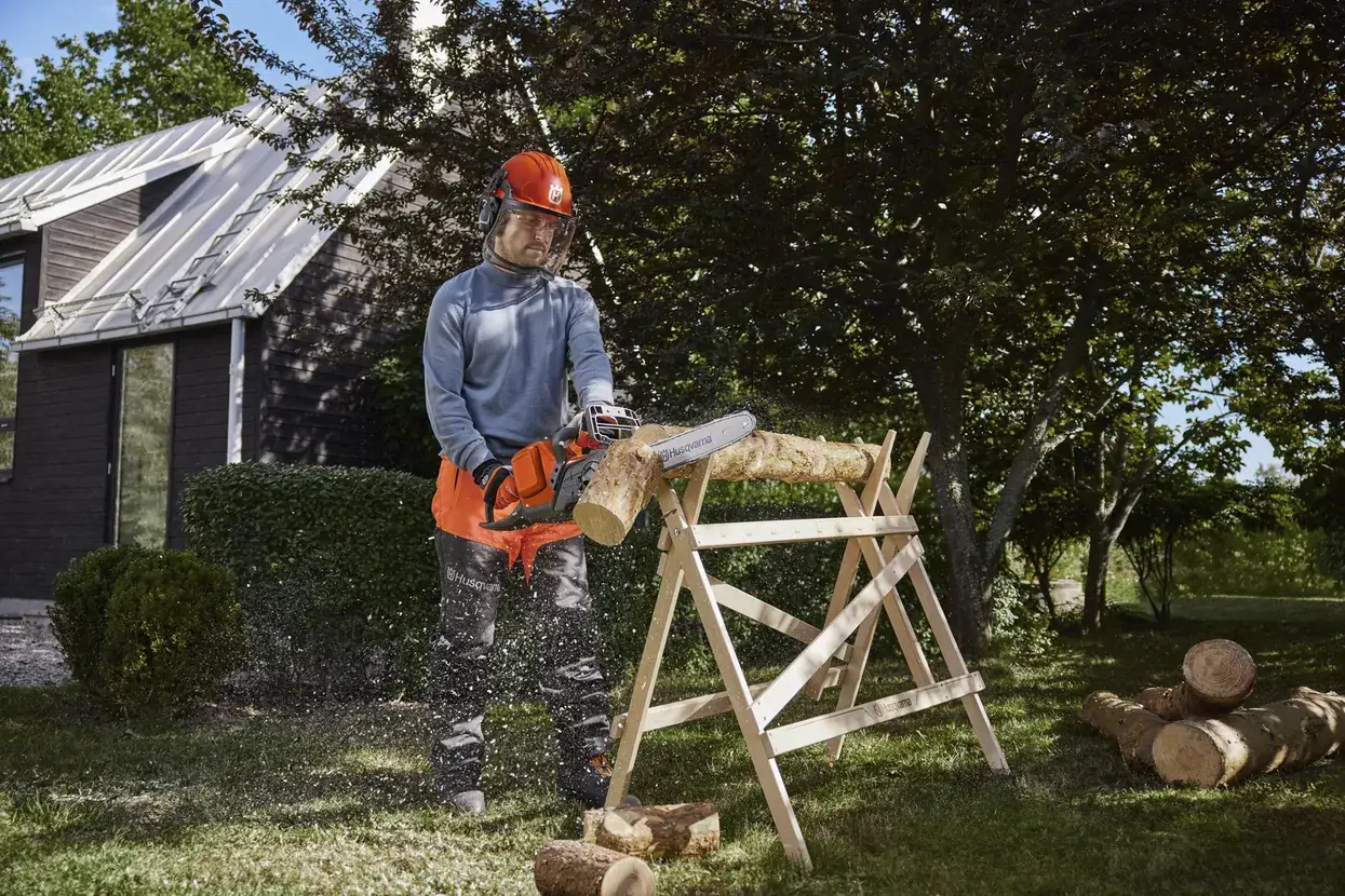 Husqvarna 240i en coupe sur un rondin, batterie BLi en place