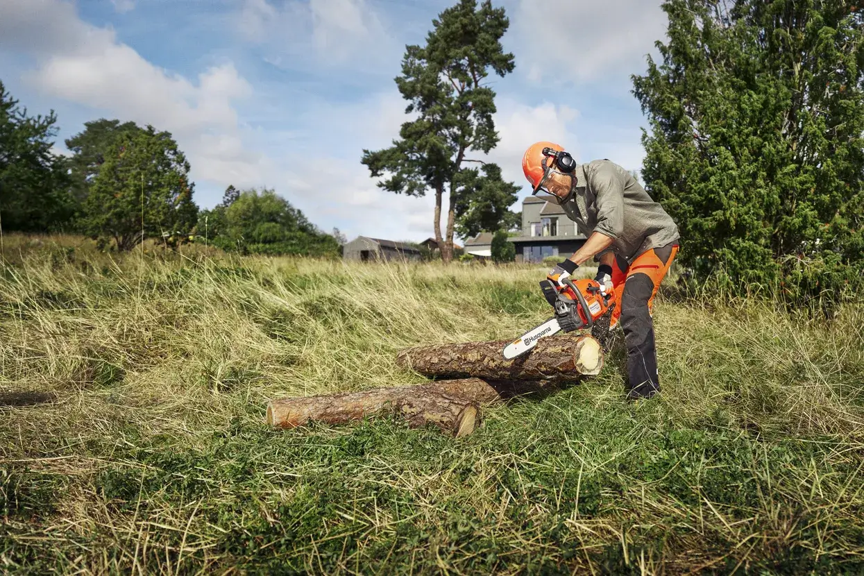 Husqvarna 445 posée près d'un tas de bûches fraîchement débitées