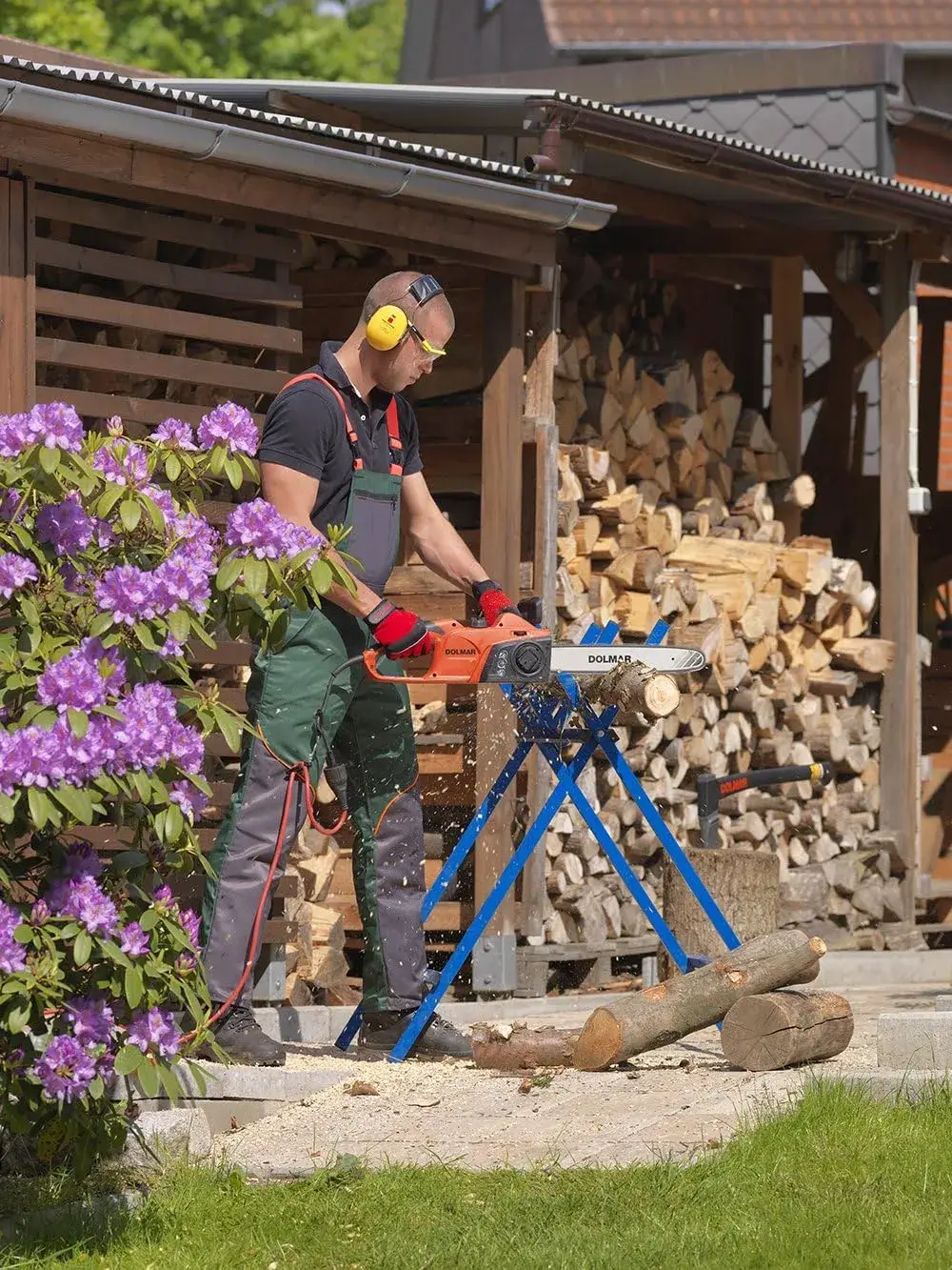 Utilisateur débitant du bois de chauffage sur chevalet avec la Dolmar ES39TLC reliée à une rallonge